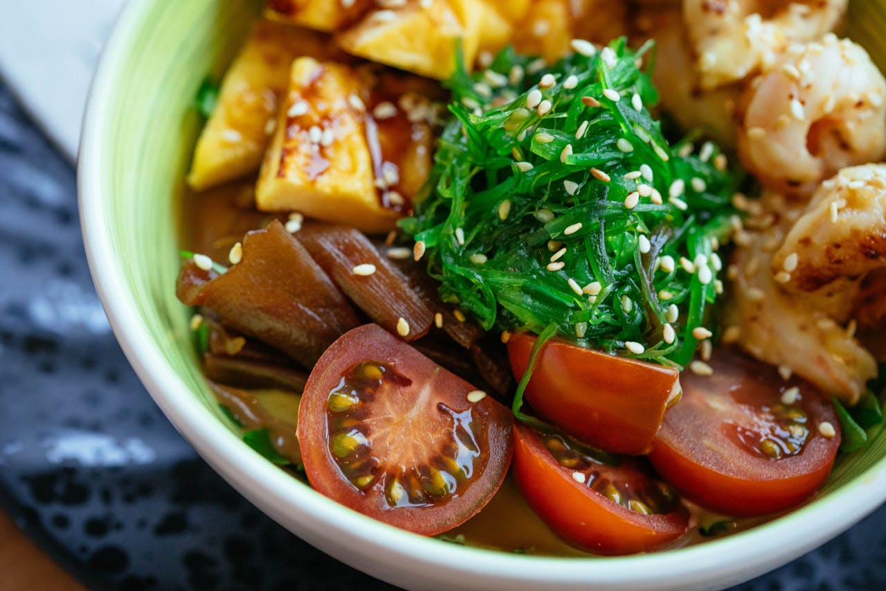 A colorful vegan poke bowl with fresh vegetables, tofu, and sesame seeds.